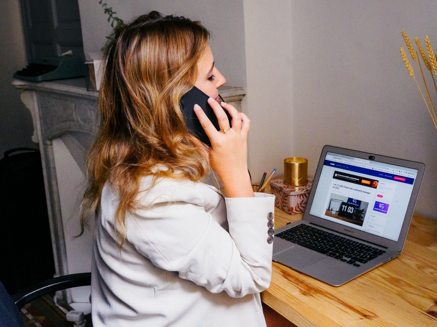 Photo: Swello on Unsplash A woman talks on the phone at a wooden desk with her laptop open beside her